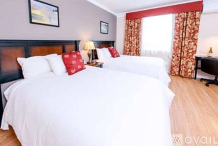 A bedroom with two beds, one with red pillows.