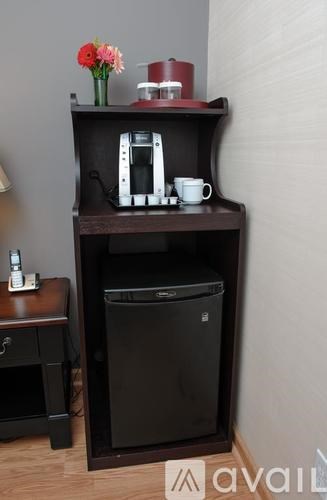 A black cabinet with a coffee maker and a cup on top.