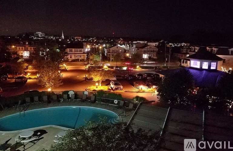 A pool surrounded by trees with a cityscape at night.