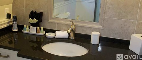 A bathroom sink with a black counter top and a white faucet.