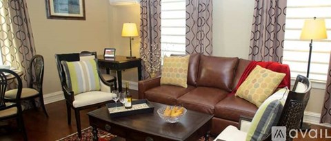 A living room with a brown leather couch and a coffee table with a tray of snacks on it.