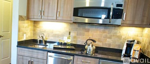 A kitchen with a black counter top and wooden cabinets.