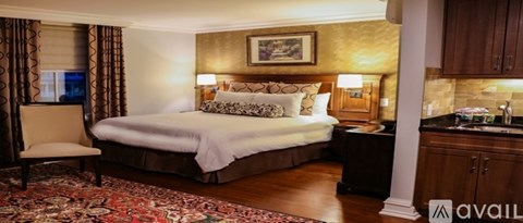 A bedroom with a large bed and a chair.