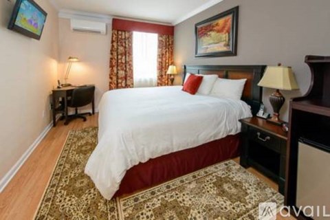 A bedroom with a large bed and a TV on the wall.