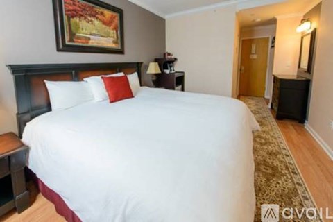 A bedroom with a large bed and a painting on the wall.