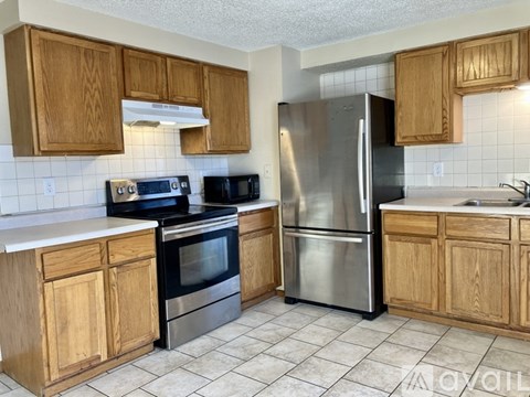 A kitchen with wooden cabinets and a stainless steel refrigerator.