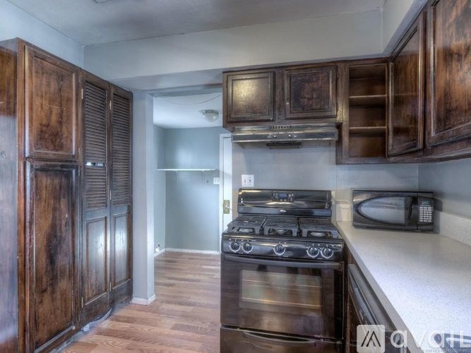 A kitchen with dark wood cabinets and a black stove top.