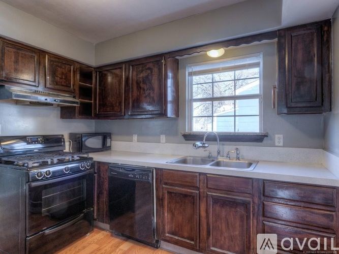 A kitchen with dark wood cabinets and a black stove top oven.