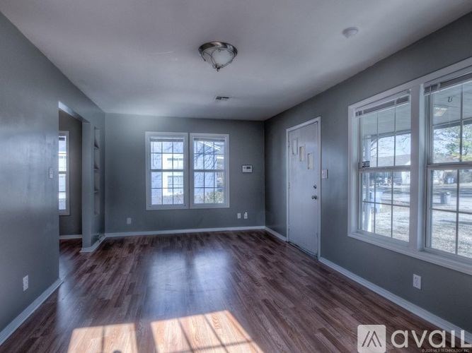 A spacious room with wooden floors and large windows.