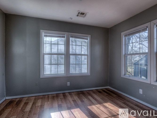 A room with two windows and wooden flooring.