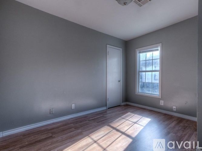 A room with a wooden floor and a window letting in sunlight.