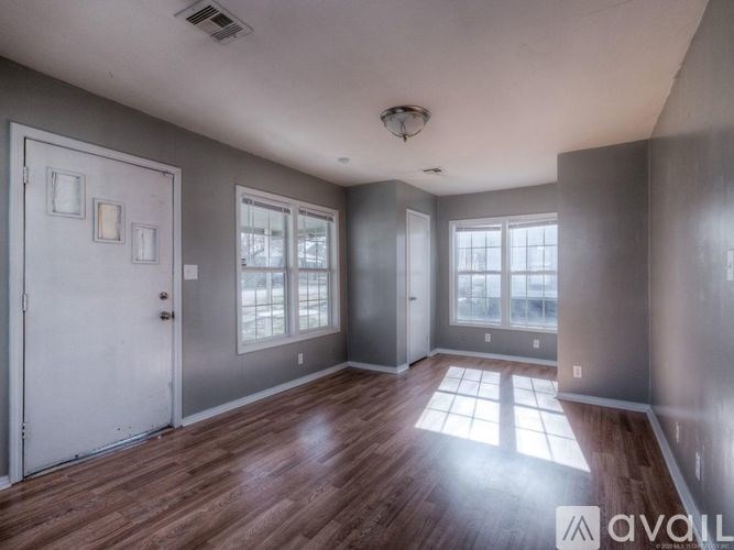 A spacious room with wooden floors and a large window.