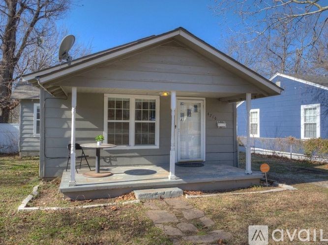 A small house with a porch and a satellite dish on the roof.
