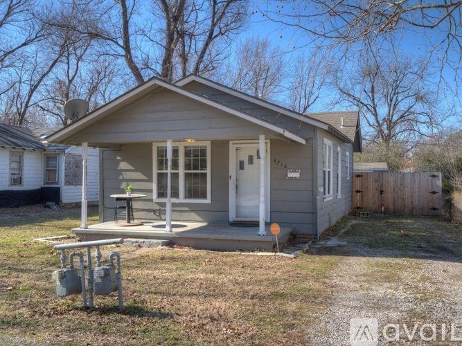 A small house with a porch and a satellite dish on the roof.