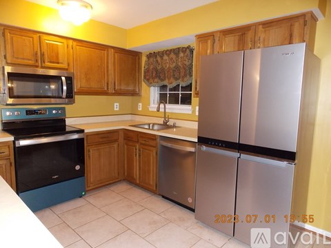 A kitchen with wooden cabinets and a stainless steel refrigerator.