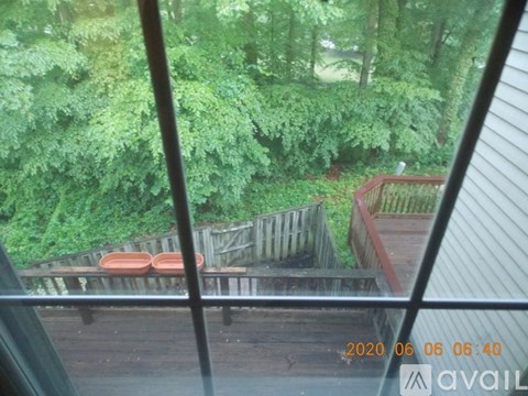A view from inside a building looking out to a wooden deck with two red chairs.
