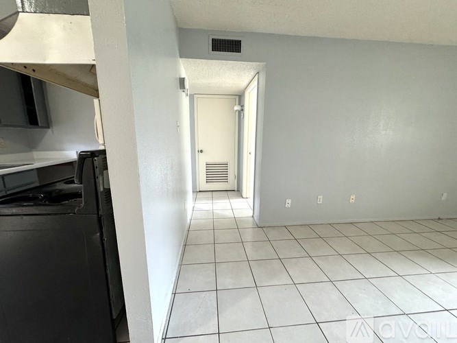 A kitchen with white tiled floors and a white door.