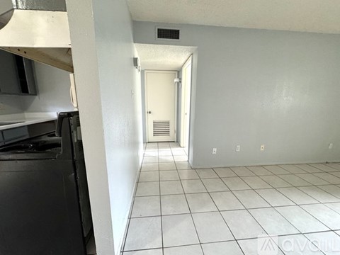A kitchen with white tiled floors and a white door.