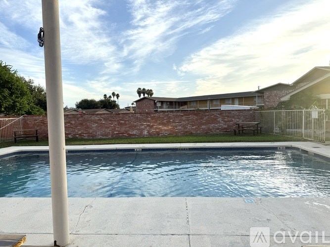 A pool with a house and a fence in the background.