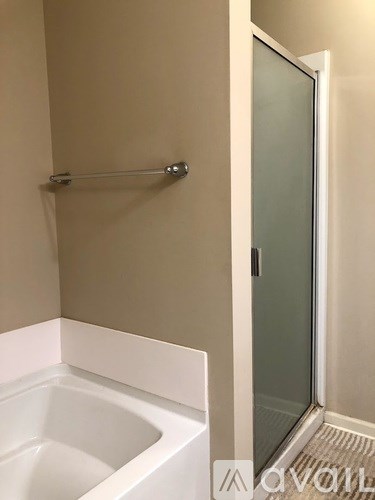 A white bathtub sits next to a glass shower door in a bathroom.