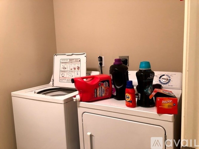 A washing machine and dryer are on a counter with a box of Bounty paper towels and some bottles of cleaning products.