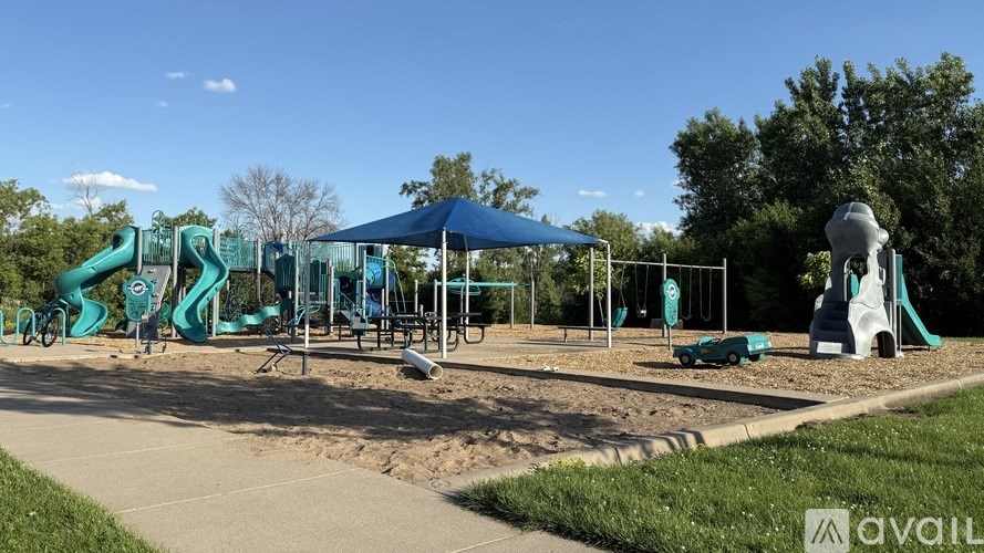 A playground with a blue canopy and a green slide.