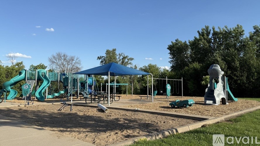 A playground with a blue canopy and a green slide.
