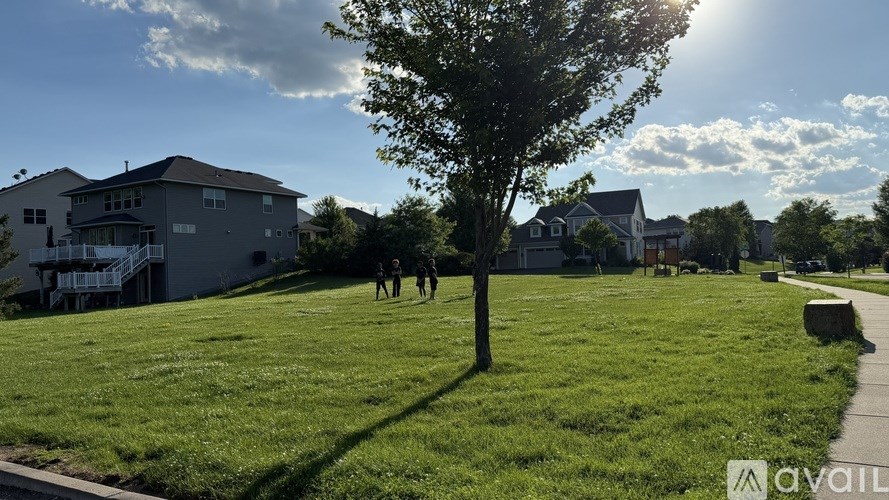 A tree in a grassy area with houses in the background.