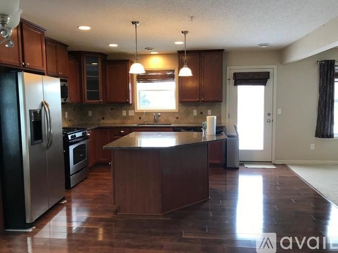 A kitchen with dark wood cabinets and a black refrigerator.