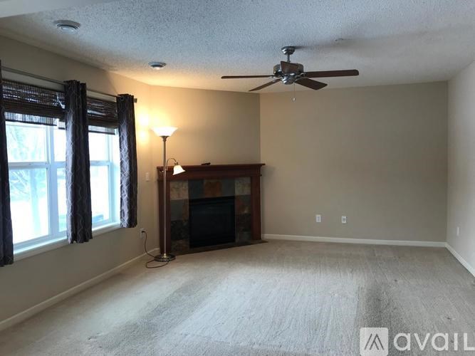 A living room with a fireplace and a fan on the ceiling.