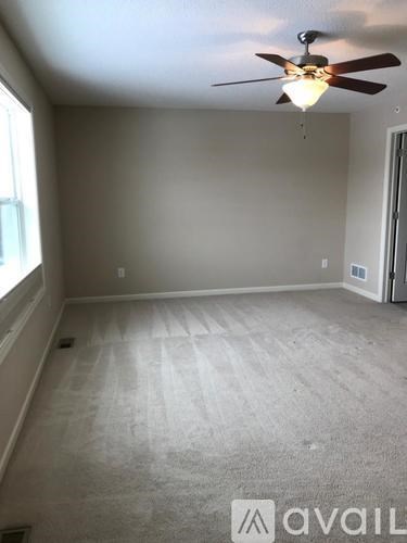 A room with a ceiling fan and carpeted floor.