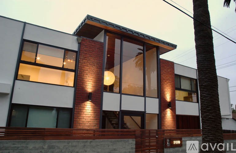 A modern house with a red brick chimney and large windows.