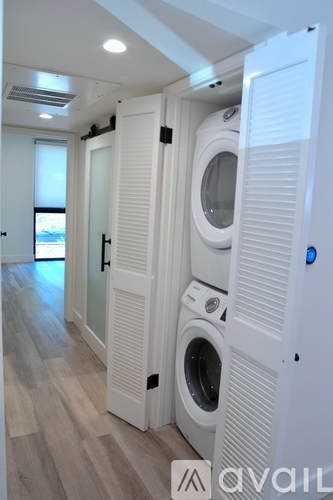 A row of white washing machines are lined up in a laundry room.