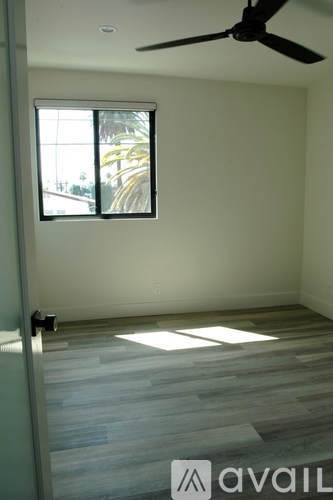 A room with a ceiling fan and a window letting in sunlight.