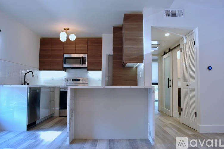 A modern kitchen with a refrigerator, microwave, and oven.