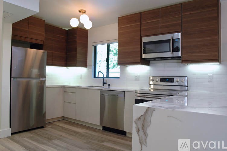 A kitchen with a refrigerator, microwave, oven, and sink.