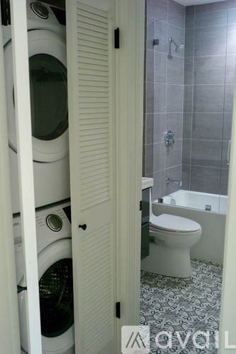 A bathroom with a toilet and a washing machine in the doorway.