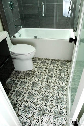A white toilet sits in a bathroom with a black and white tiled floor.