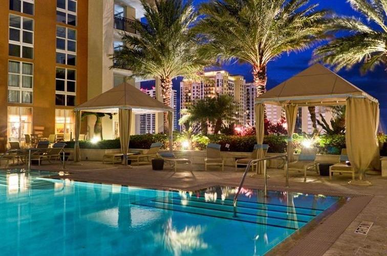A pool area with a gazebo and palm trees at night.