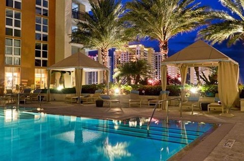 A pool area with a gazebo and palm trees at night.