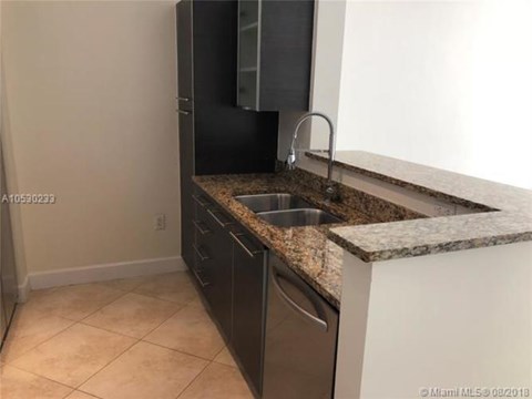 A kitchen with a granite counter top and black appliances.