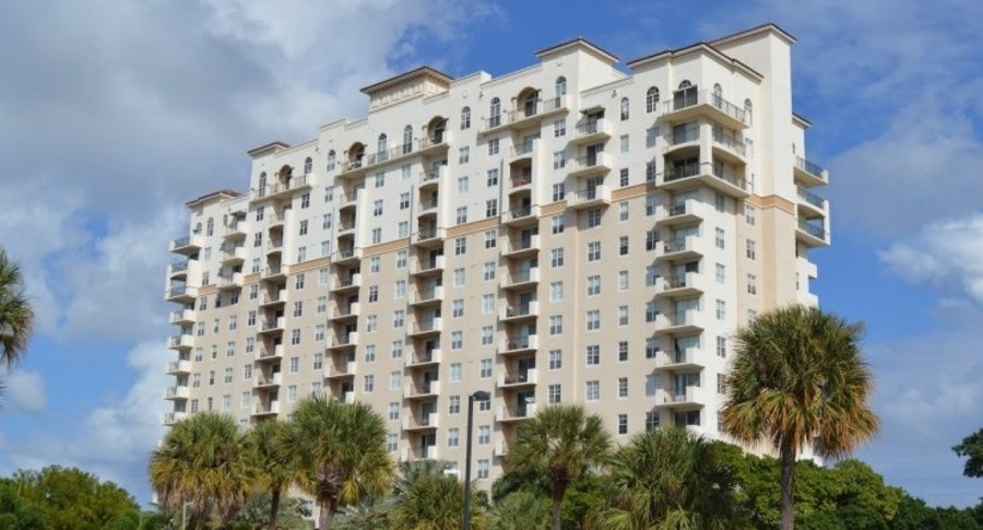 A large white apartment building with balconies and multiple stories.