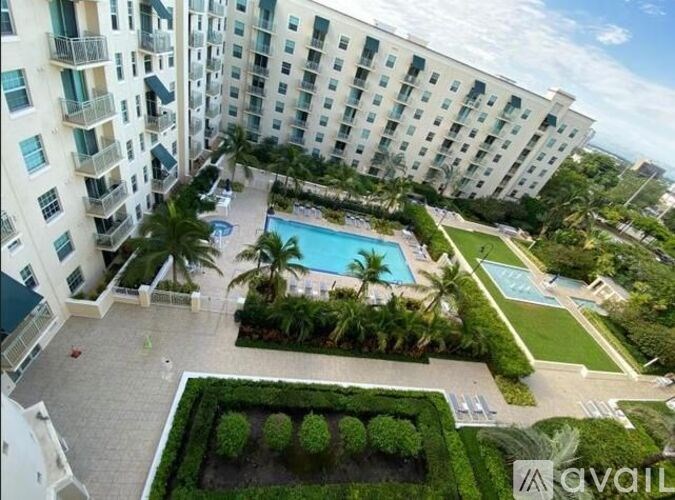 A large white building with a pool and greenery.