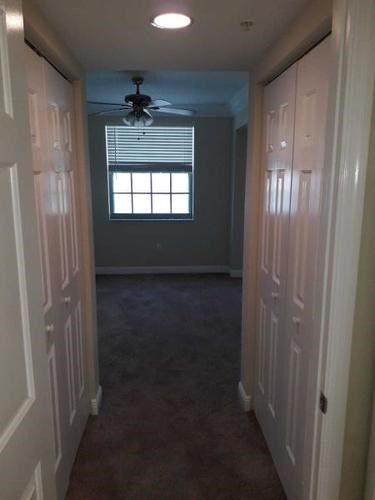 A long hallway with a fan and a window.