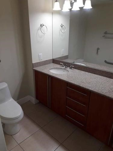 A bathroom with a toilet, sink, and mirror.