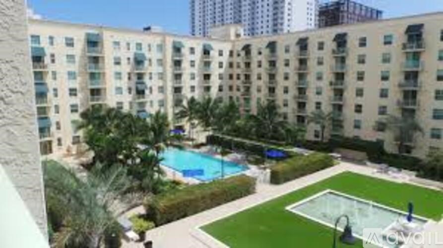 A large apartment complex with a pool and a green lawn.