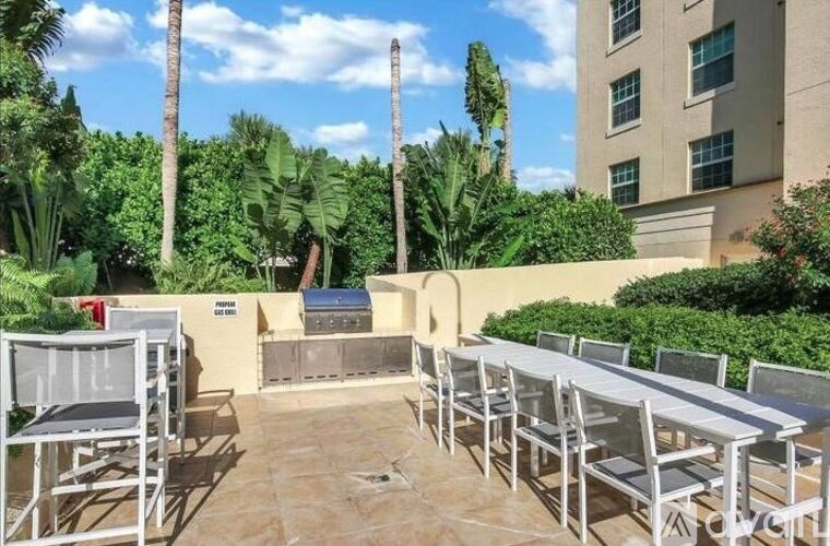 A patio with chairs and a table surrounded by greenery.