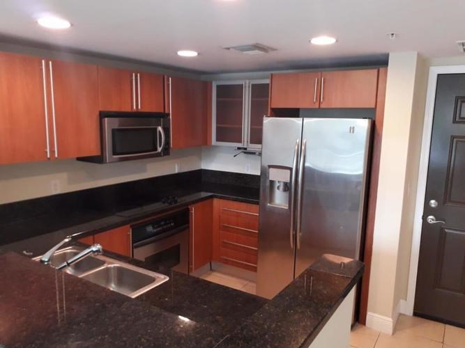 A kitchen with a black granite counter top and stainless steel appliances.