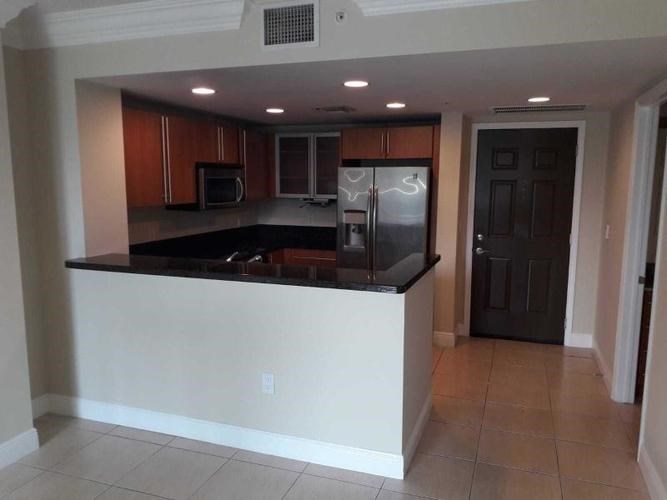 A kitchen with brown cabinets and a black counter top.