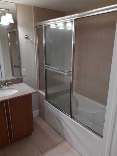 A bathroom with a sink, mirror, and shower.